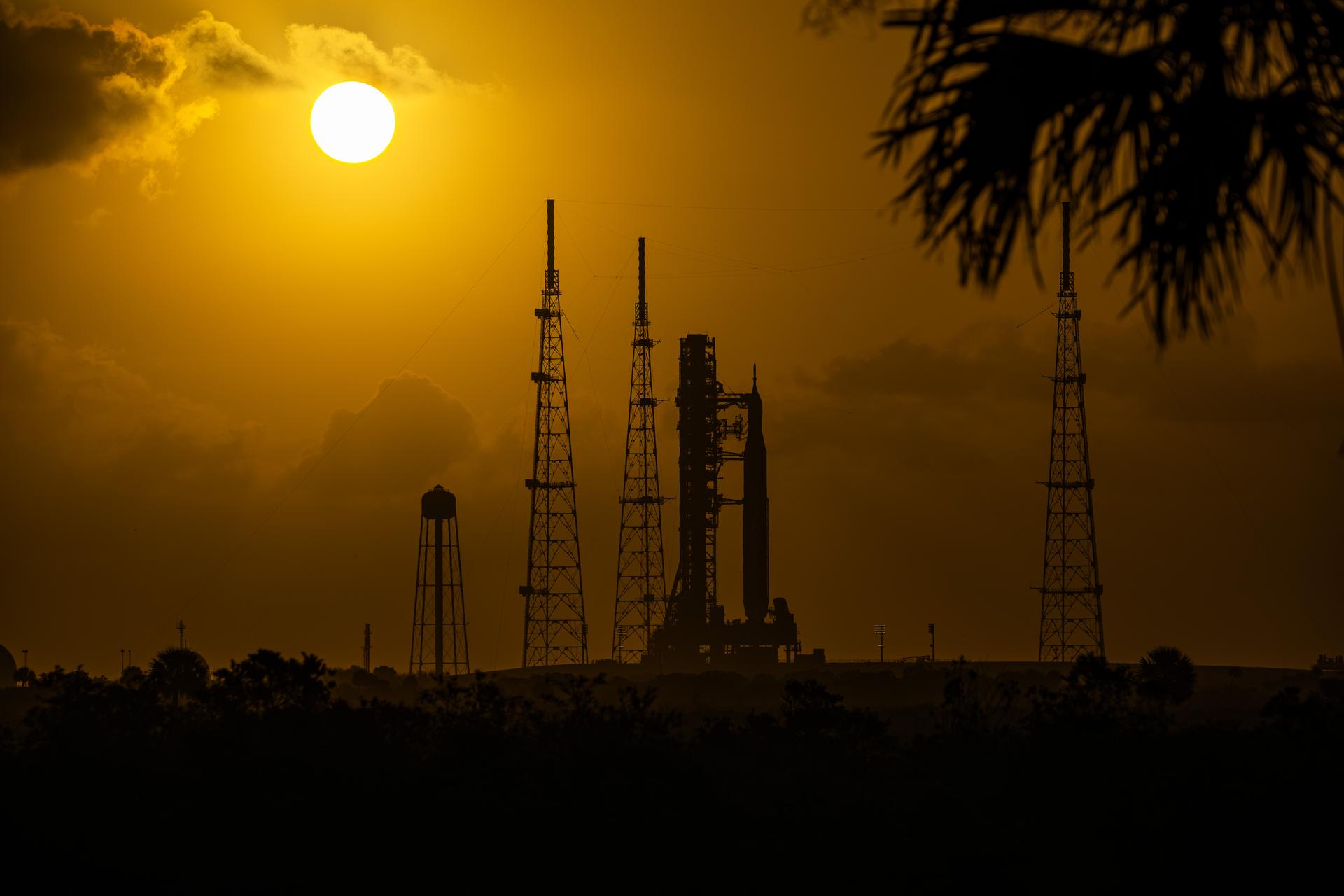 This image shows a sunset of NASA’s SLS (Space Launch System) and Orion spacecraft at NASA’s Kennedy Space Center. NASA's massive Crawler-Transporter, upgraded for the Artemis program, carried the powerful SLS rocket and Orion spacecraft on the Mobile Launcher from the Vehicle Assembly Building to Launch Pad 39B at Kennedy Space Center in preparation for the Artemis II mission.